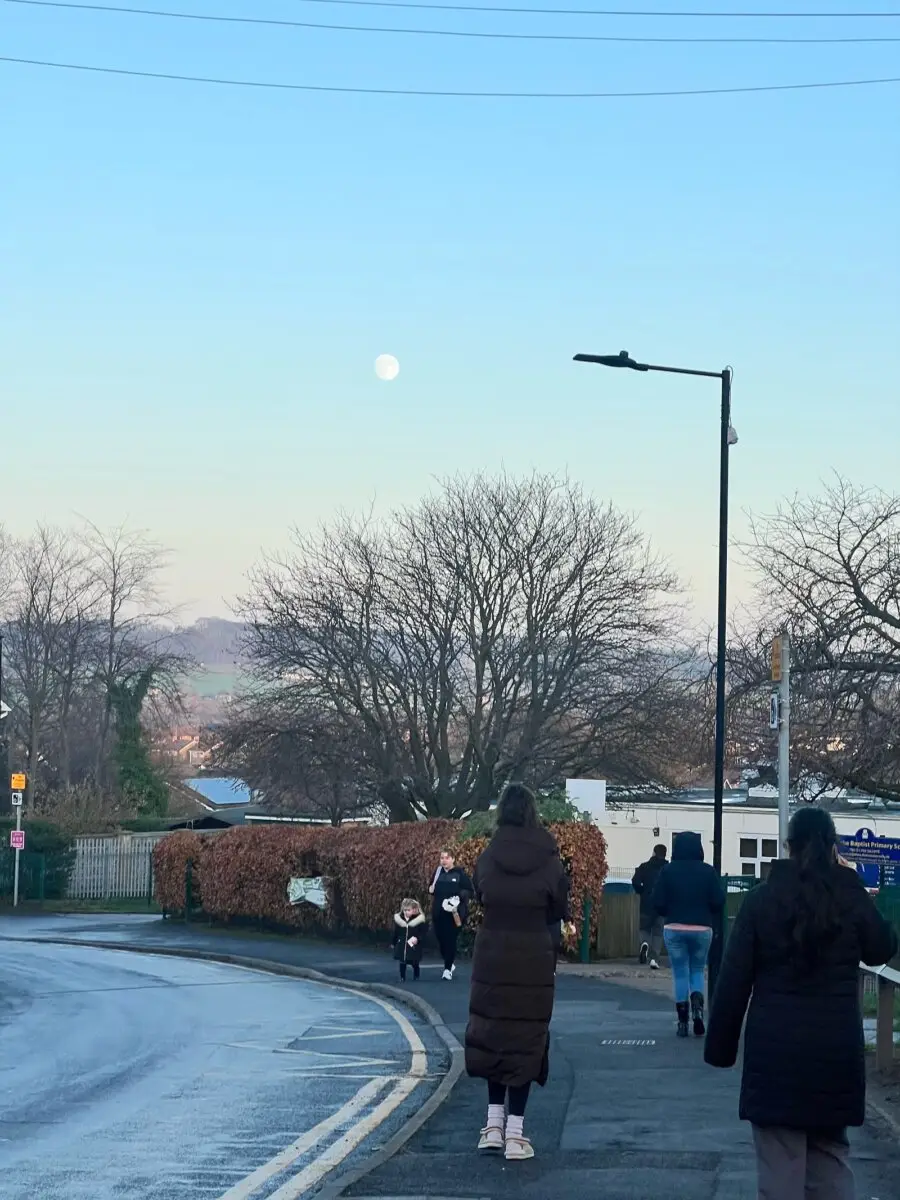 Original unedited photo of the daytime moon above Mexborough with people walking outside a primary school — before Lightroom Mobile object removal editing